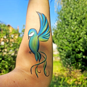 Dessin coloré d’un oiseau peint sur l’intérieur d’un bras lors d’une séance de bodypainting artistique.