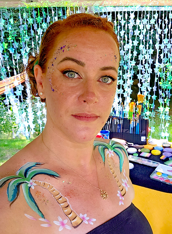 Léa maquillée de palmiers et de paillettes pendant un événement festif en extérieur, peu avant l’orage.