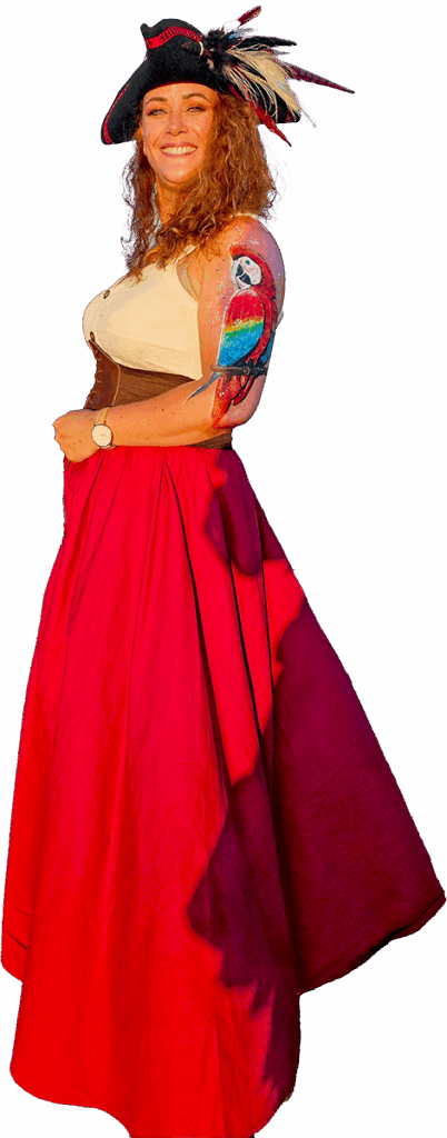 Léa Lafarge, maquilleuse artistique, déguisée en pirate avec un body painting de perroquet coloré sur le bras, souriante au bord de l’océan.