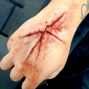 Maquillage effet spécial de plaie ouverte en silicone sur la main, pour tournage ou Halloween.