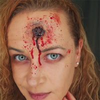 Léa Lafarge avec un maquillage d’effets spéciaux réaliste représentant une blessure ensanglantée au front, démontrant ses compétences en SFX artistiques.